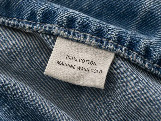 Care label on denim reading 100% cotton, machine wash cold